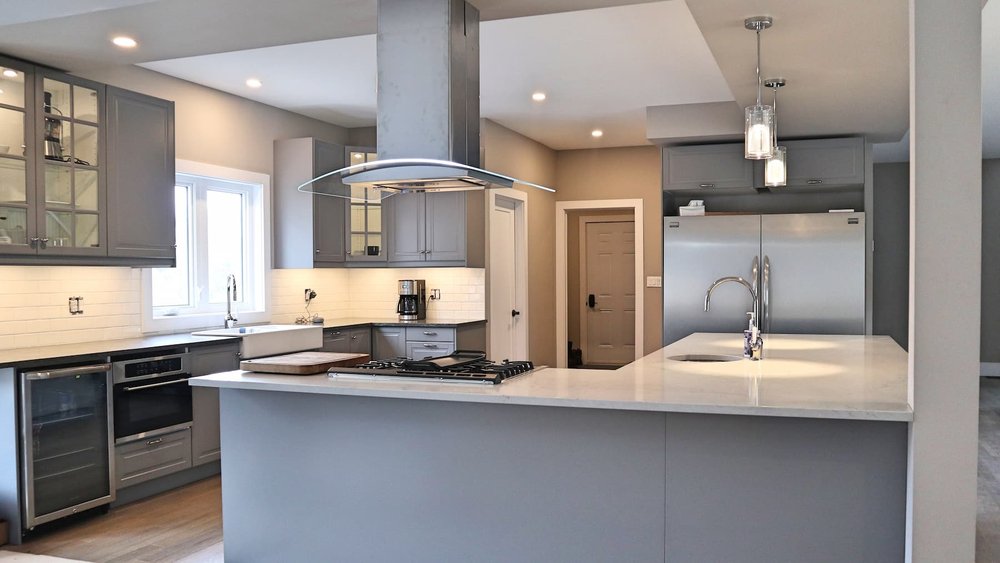 Grey modern kitchen renovation in Toronto with curved range hood