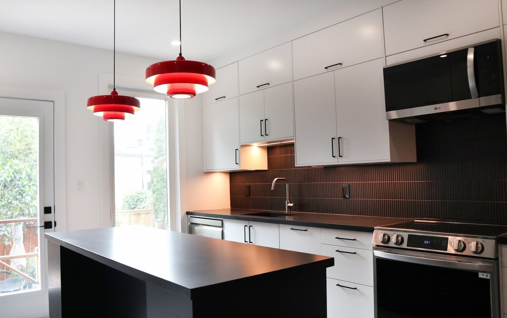 Modern kitchen renovation in Toronto with white cabinets and dark contrast counter
